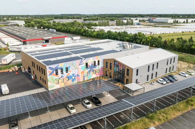 The Okamac site seen from the air: workshop, offices and solar canopies over the car park